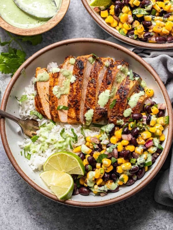 Southwest chicken and rice bowl with black bean corn salsa and cilantro lime dressing in a white bowl with a fork.