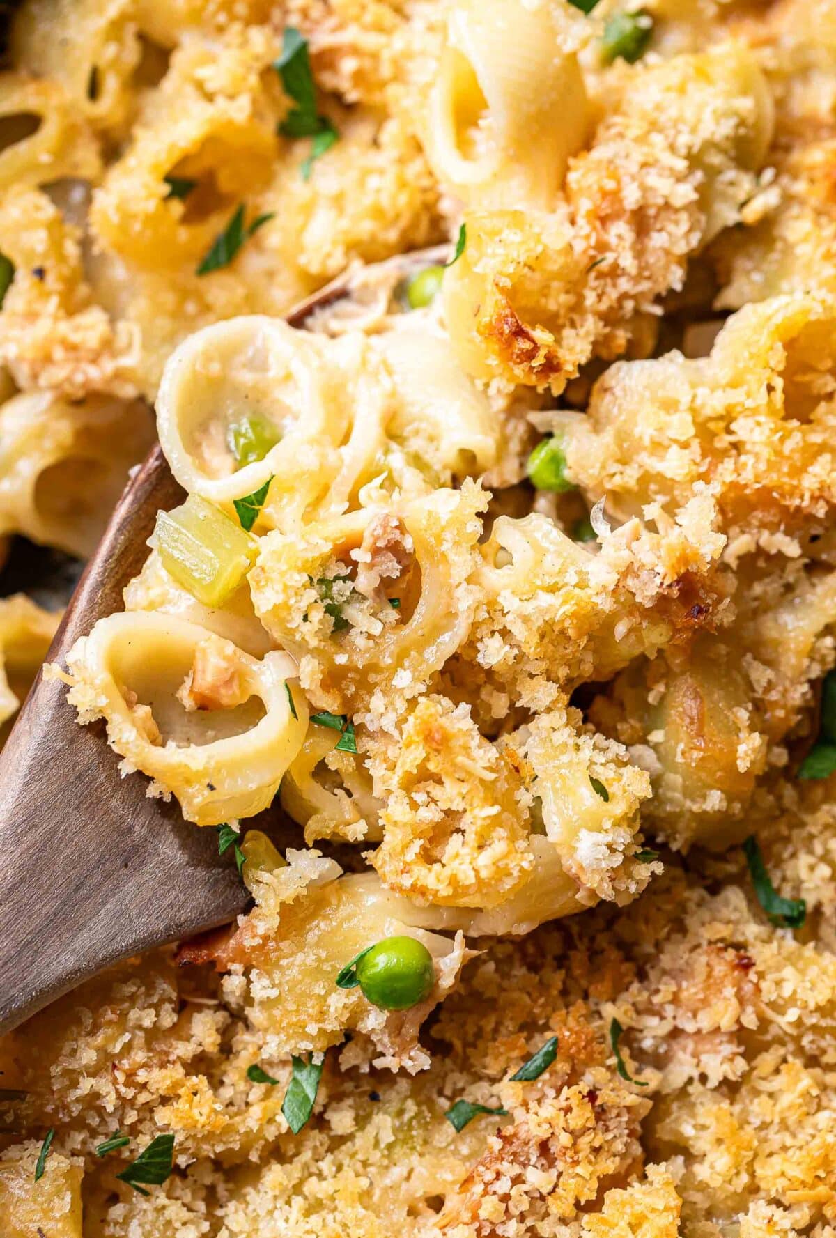 Wooden spoon holding a scoop of tuna casserole.