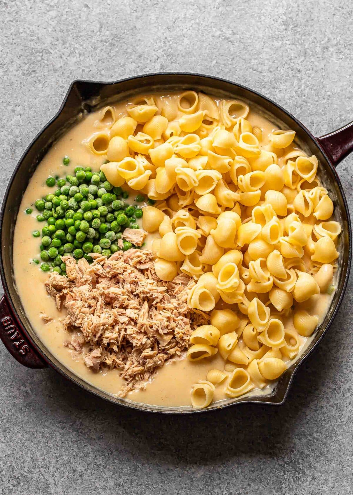 Pasta, tuna, peas, and cream sauce in a skillet.