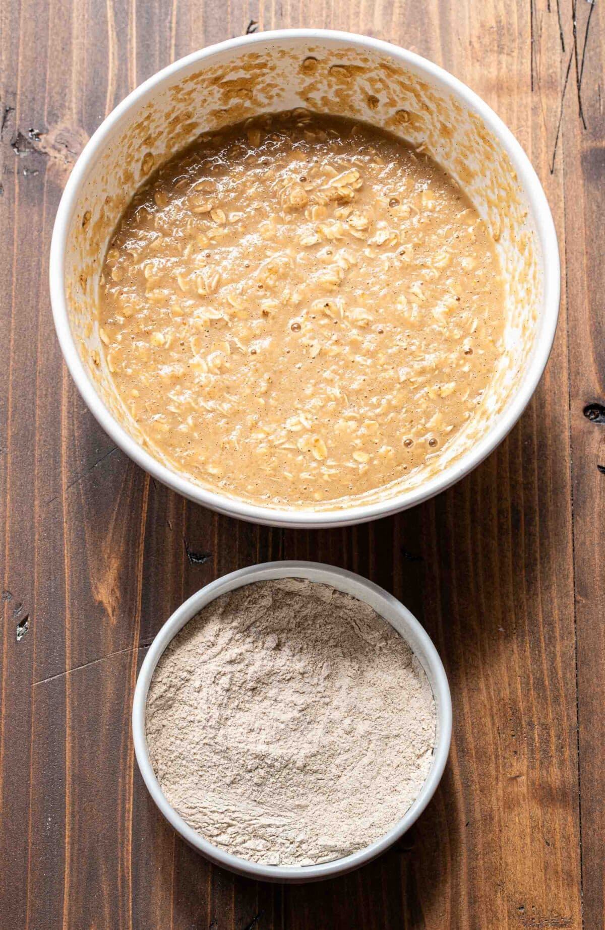 Wet ingredients for applesauce muffins in a large white bowl and dry ingredients in a small white bowl.