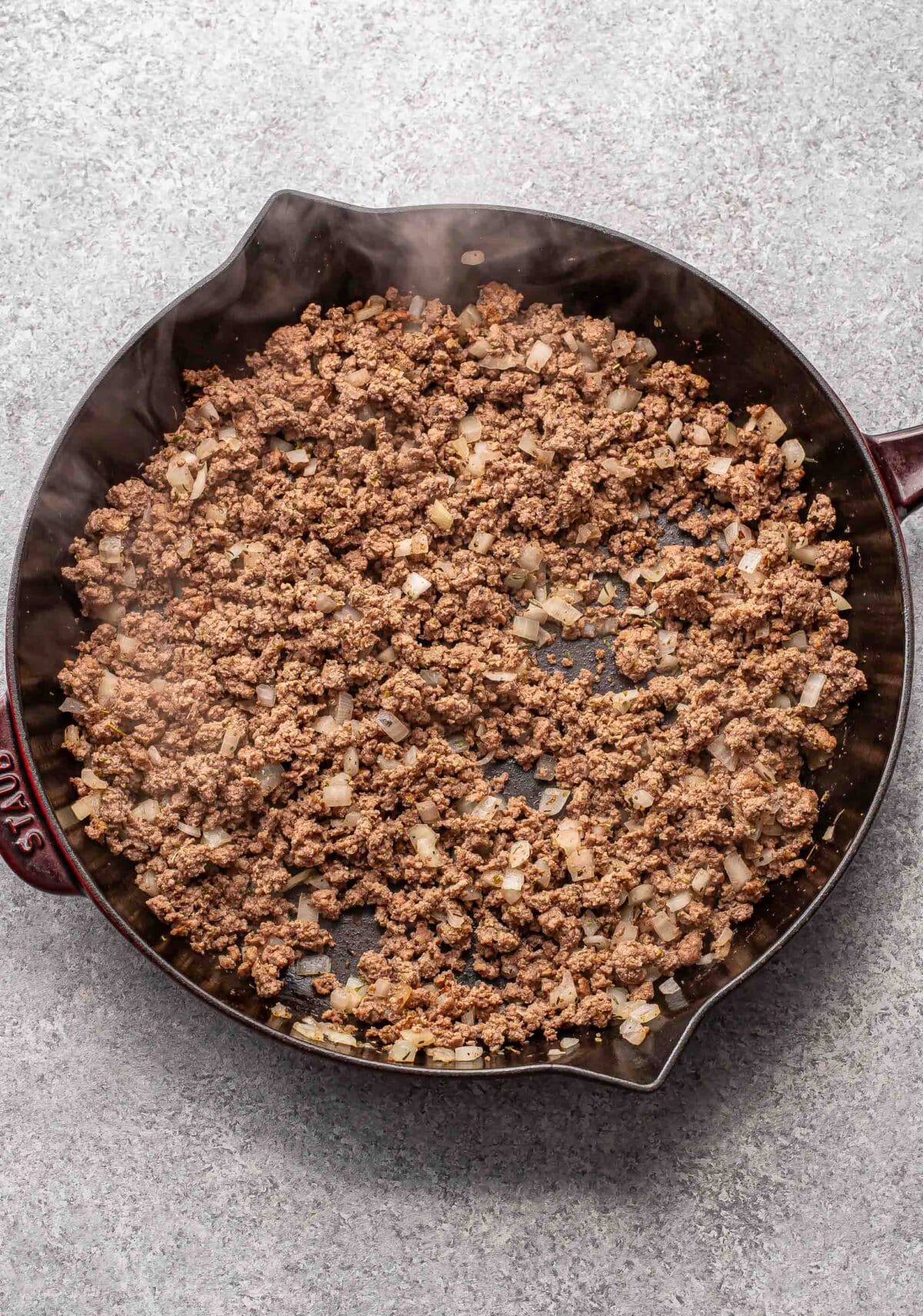 Crumbled ground beef and onions in a skillet.