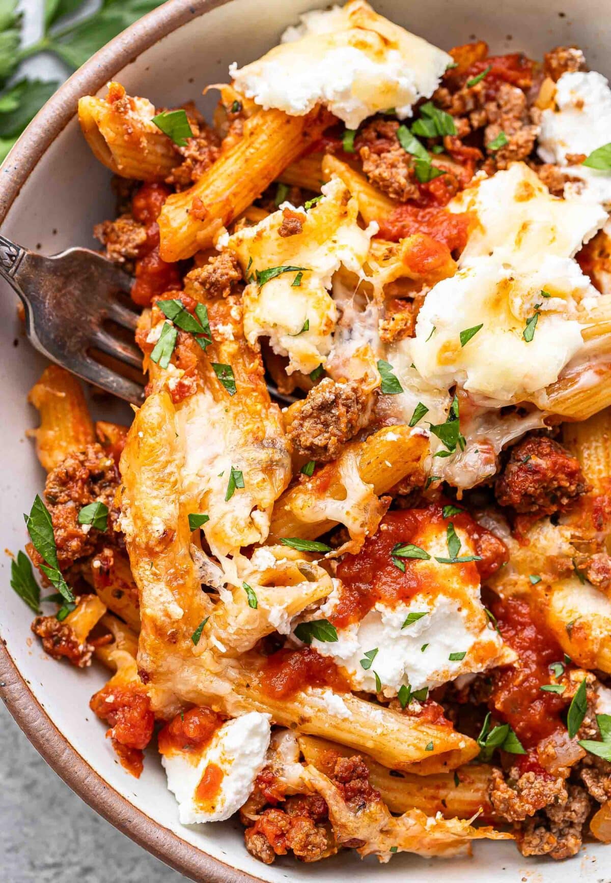 Baked penne with ricotta in a white bowl with a fork.