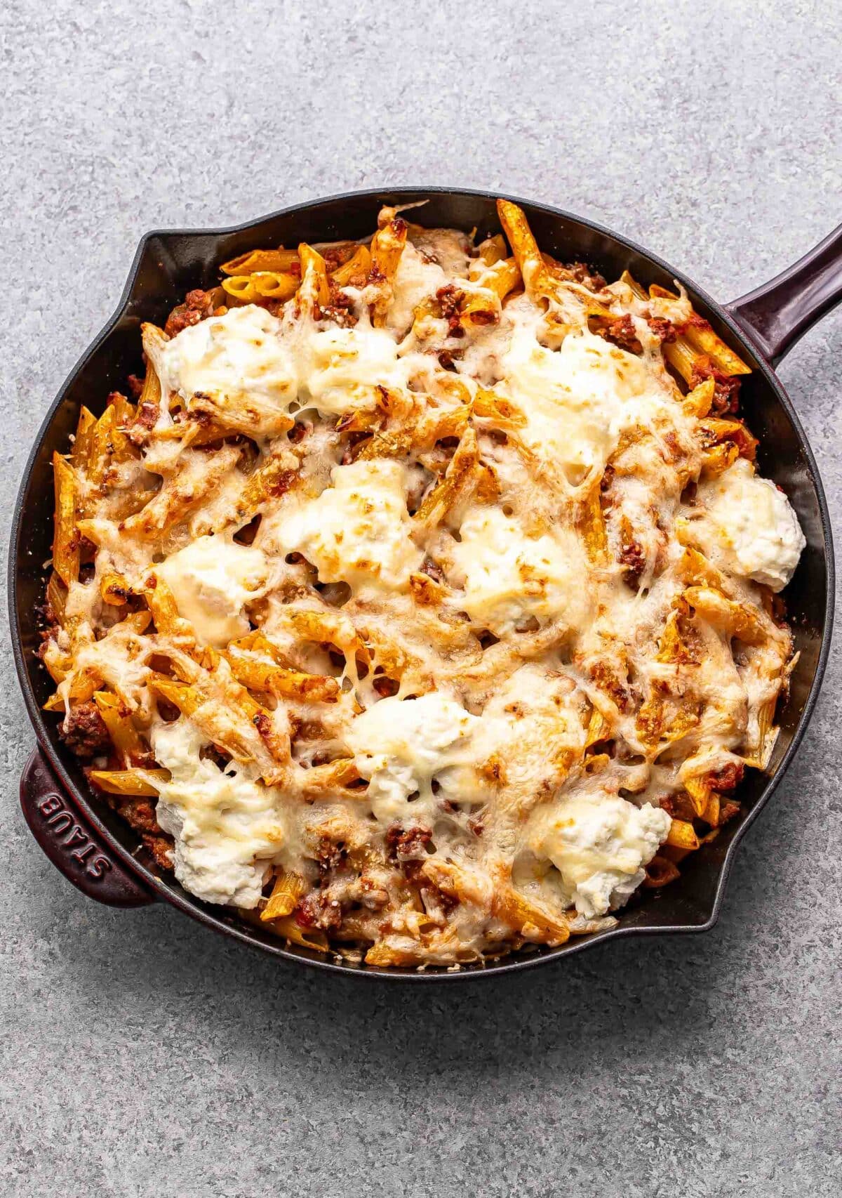 Baked penne with ground beef and ricotta cheese in a skillet.