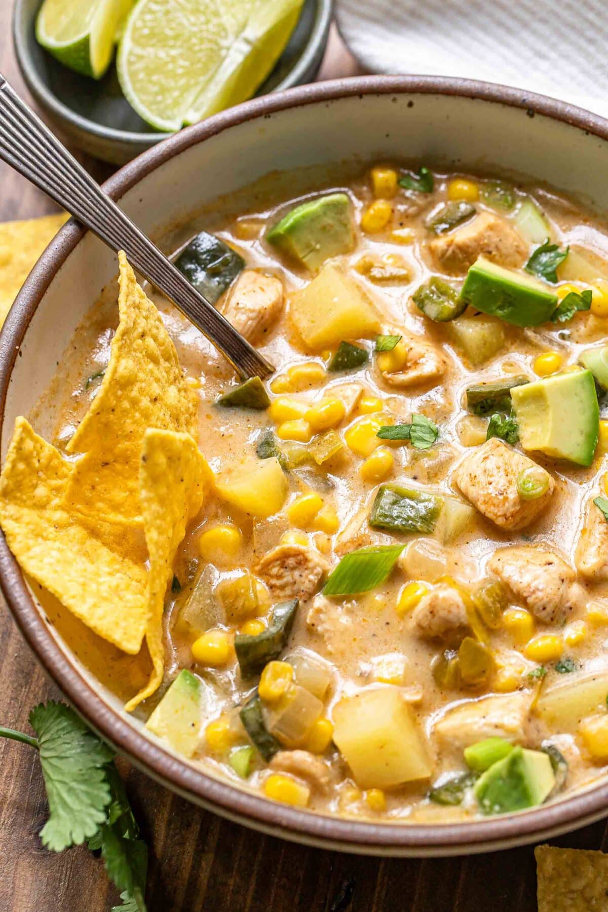Chicken corn chowder in a bowl topped with avocado and tortilla chips.