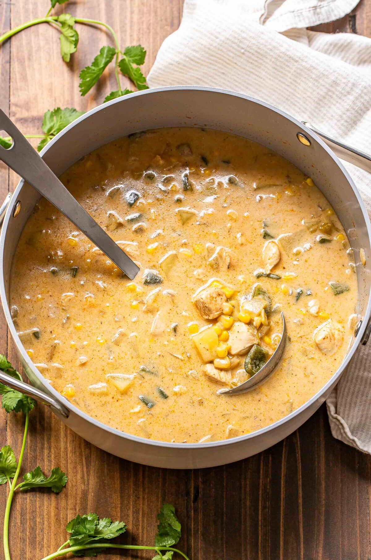 A pot of chicken corn chowder with a ladle in it.