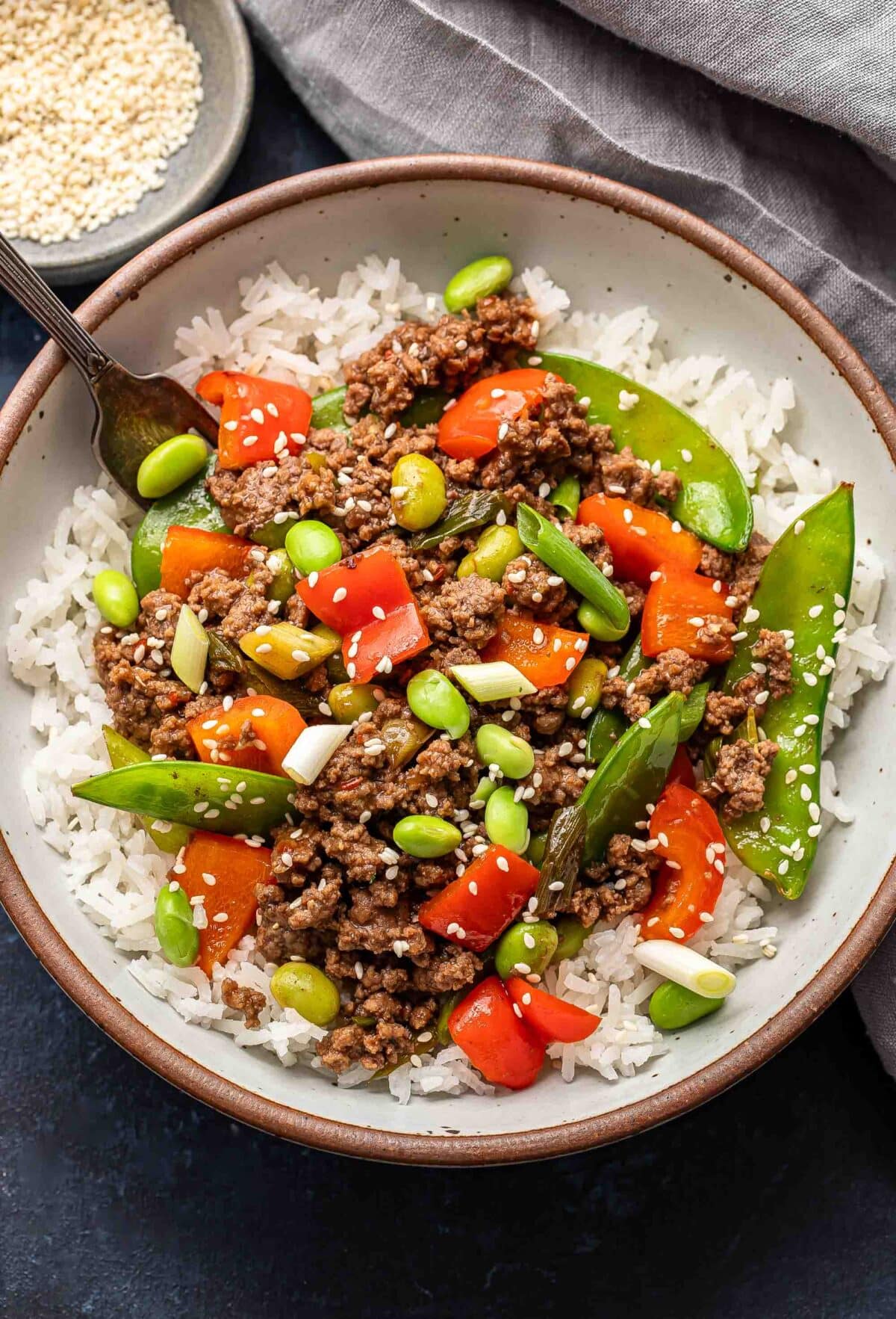 Ground beef stir fry with veggies on top of white rice.