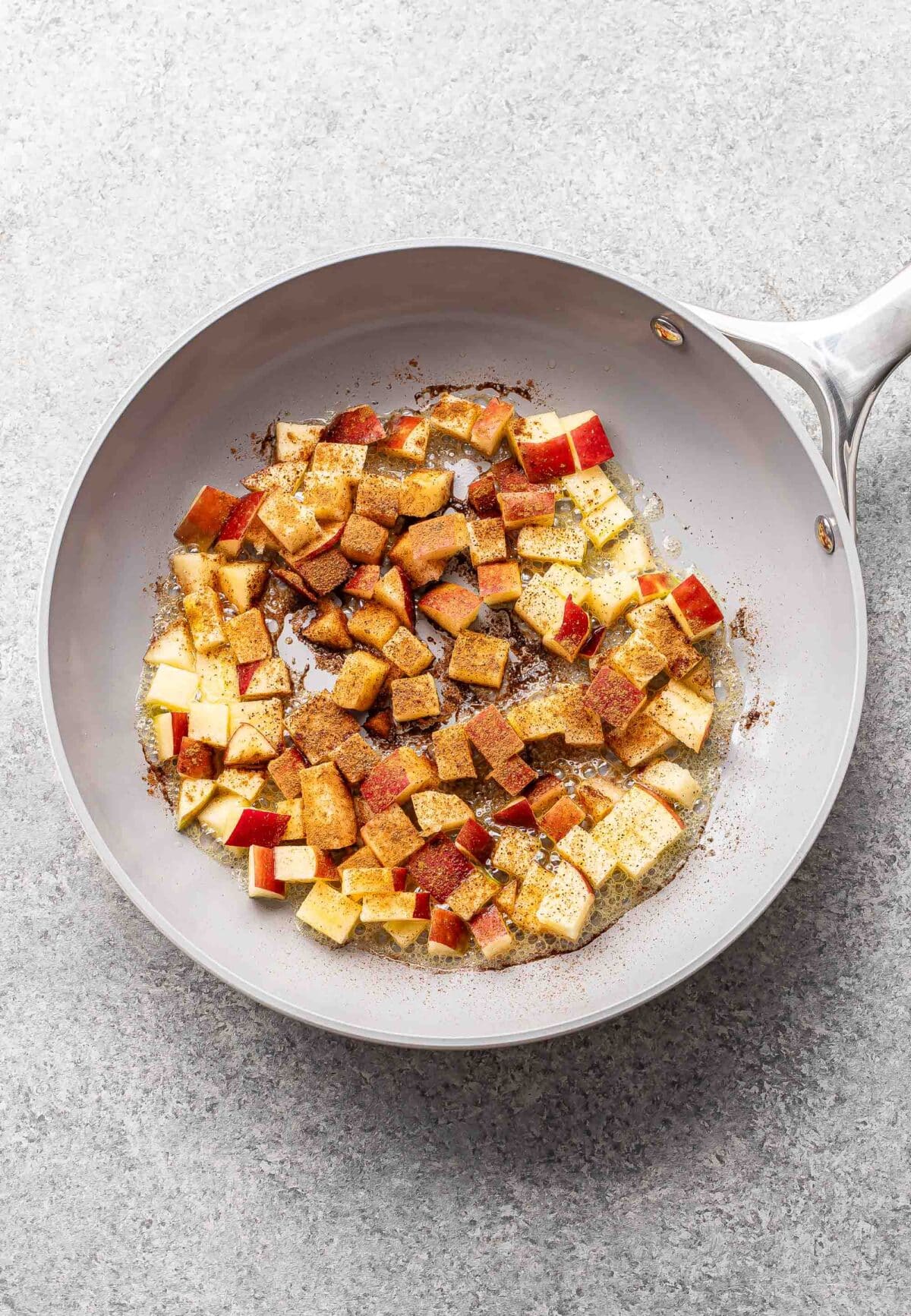 Diced apples in a skillet with cinnamon.
