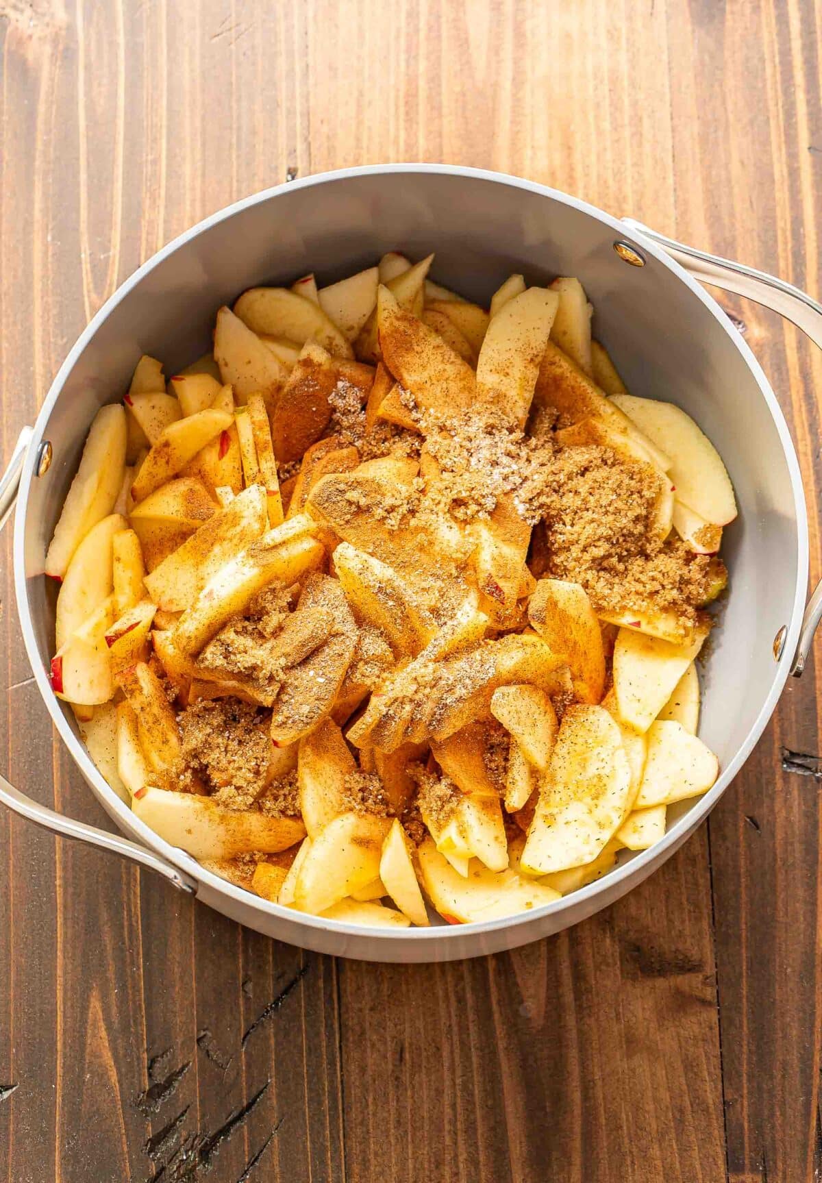 Sliced apples in a pot with cinnamon and brown sugar.