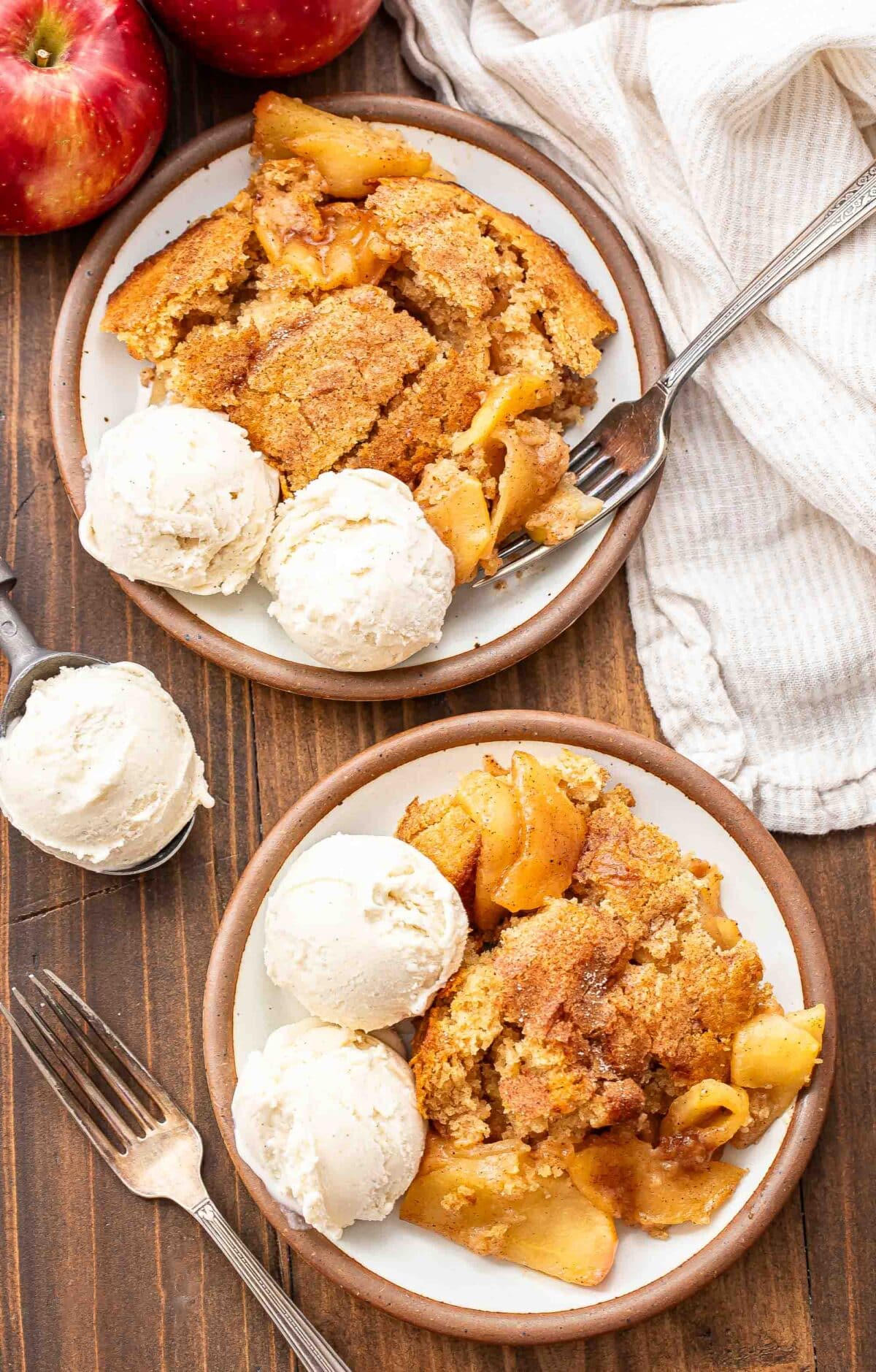 Two plates with apple cobbler and vanilla ice cream on them.