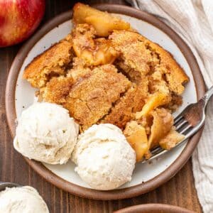 A white plate with apple cobbler and vanilla ice cream on it.