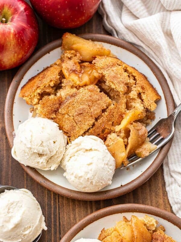 A white plate with apple cobbler and vanilla ice cream on it.
