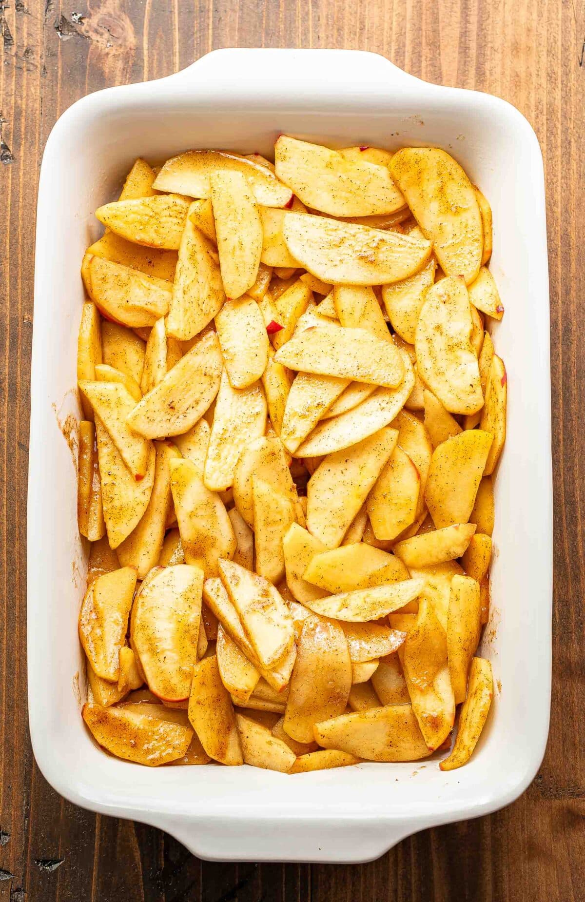 Cooked apples in a white baking dish.