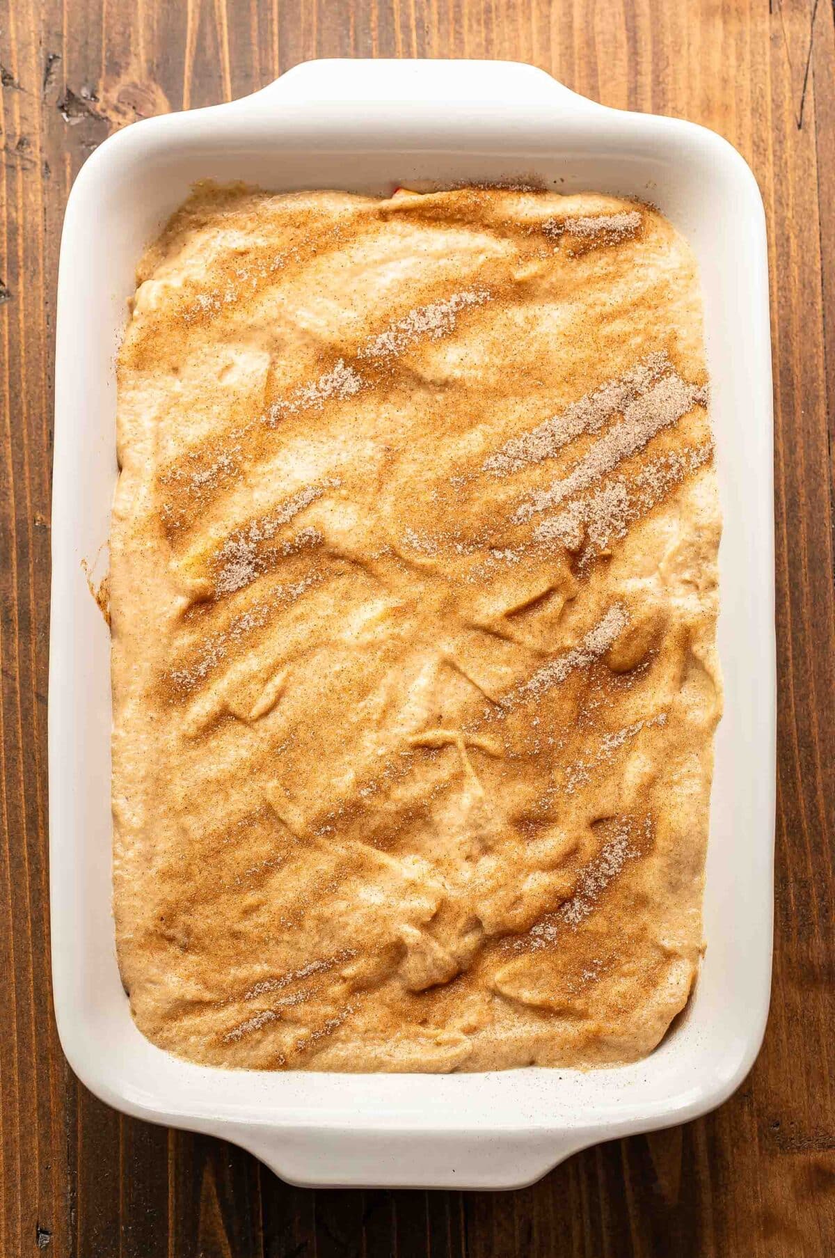 Apple cobbler before it's been baked in a white baking dish.