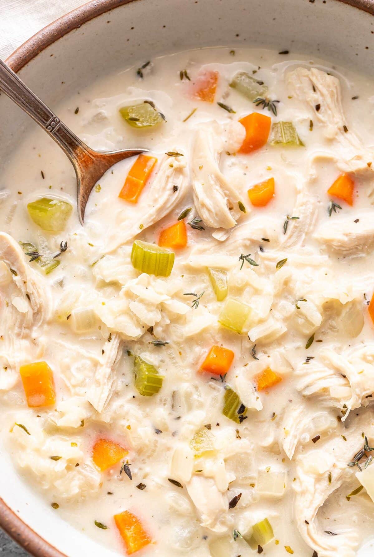 Creamy chicken and rice soup in a bowl with a spoon.