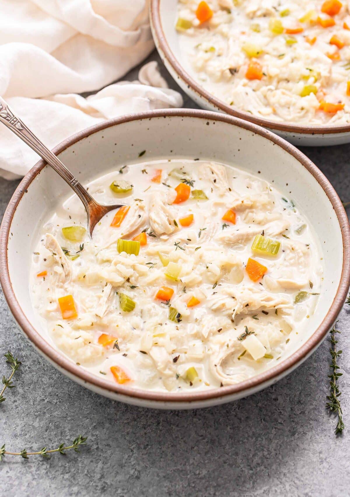 White bowl with a spoon and creamy chicken and rice soup in it.