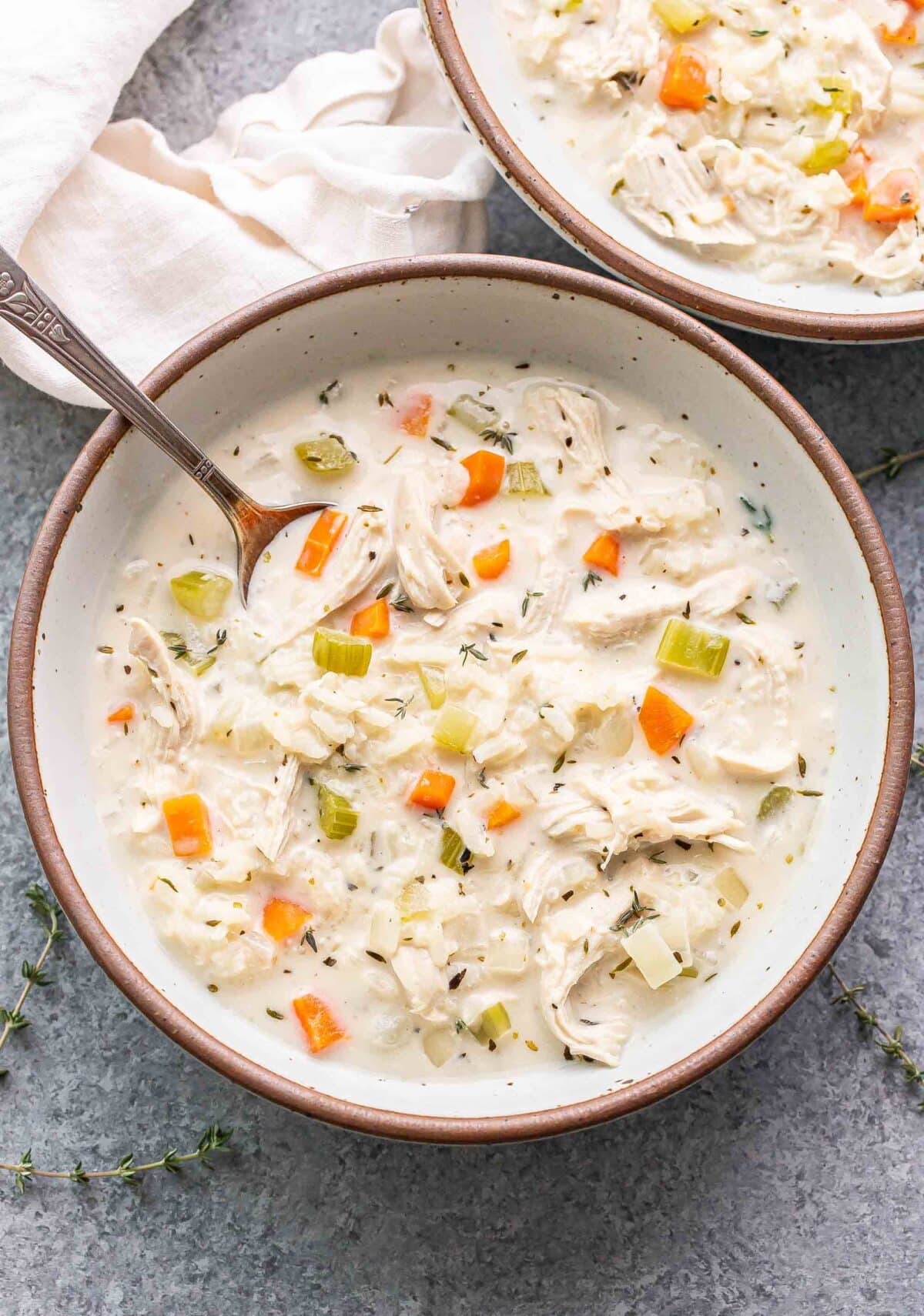 Creamy chicken and rice soup in a white bowl with a spoon in it.