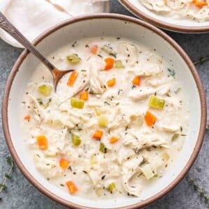 Creamy chicken and rice soup in a white bowl with a spoon in it.