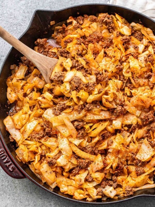 Ground beef and cabbage in a skillet with a wooden serving spoon.