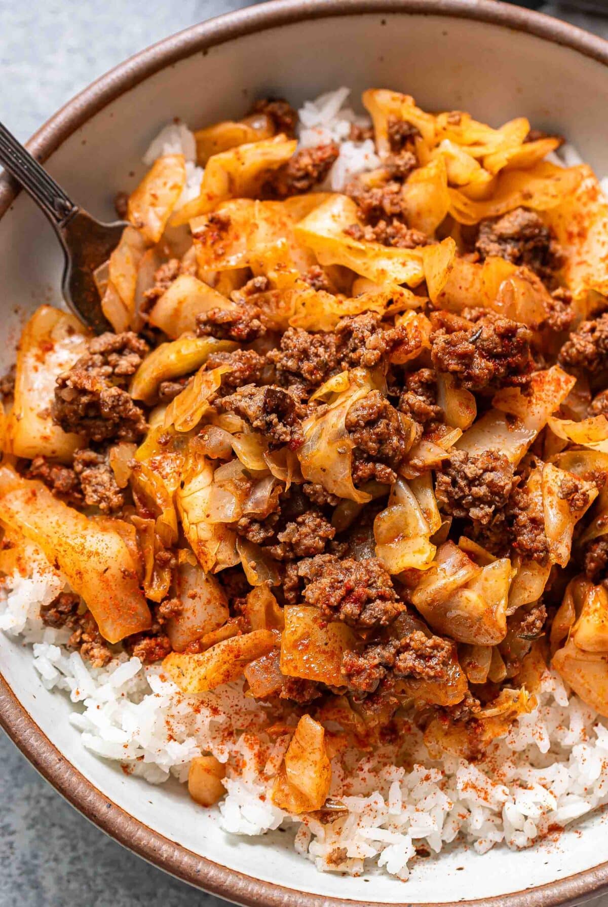 Ground beef and cabbage on top of rice in a bowl.