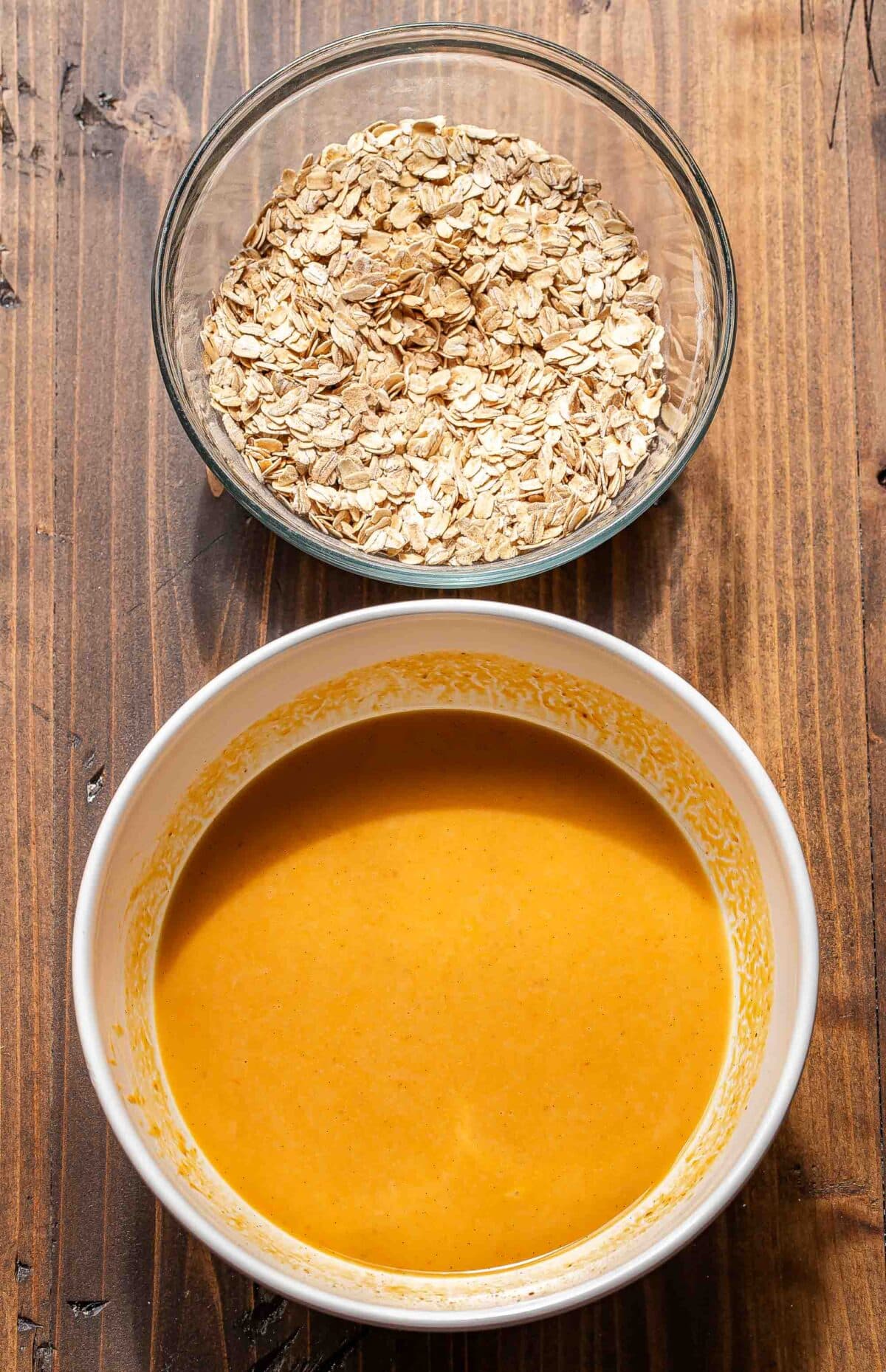 A bowl of pumpkin puree, milk, eggs and sugar and another bowl with oats and spices.