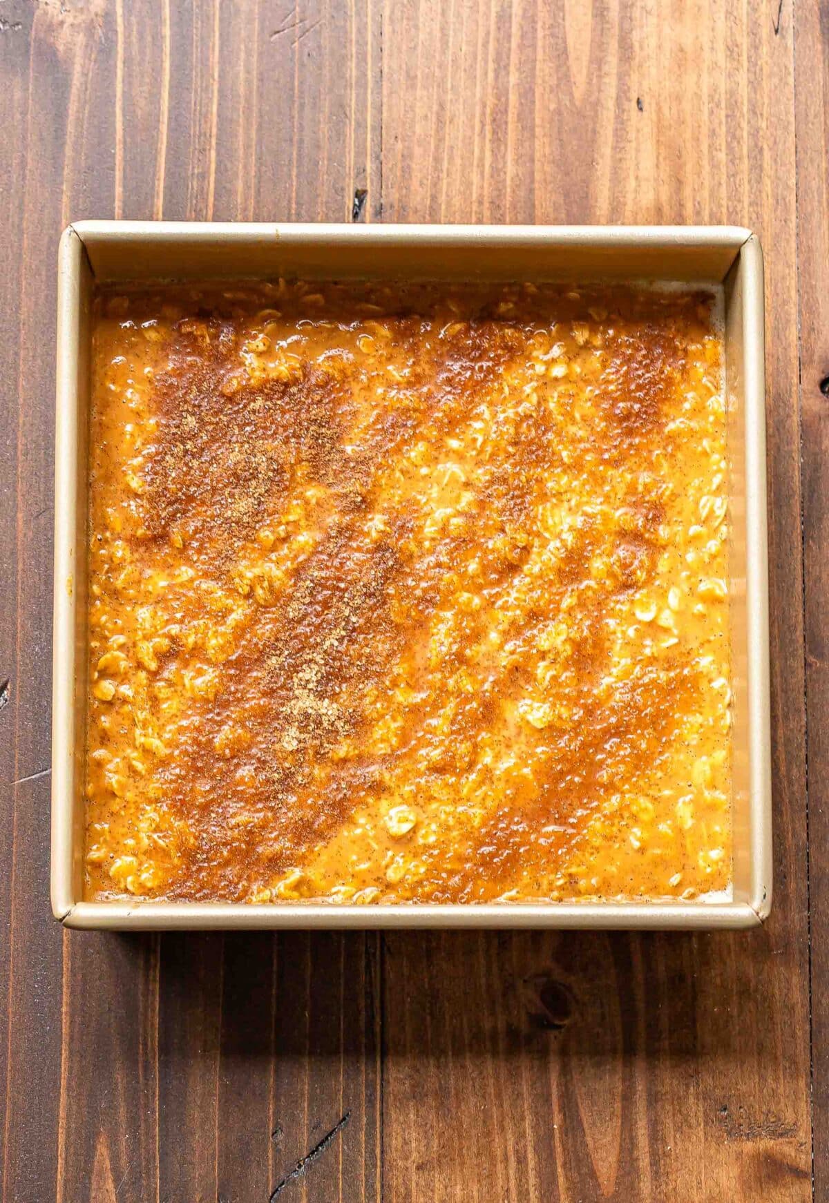 Pumpkin baked oatmeal topped with cinnamon sugar in an square baking pan before it's been baked.