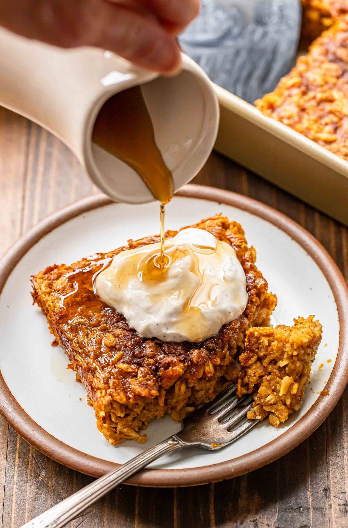 Maple syrup being poured onto a piece of pumpkin baked oatmeal.