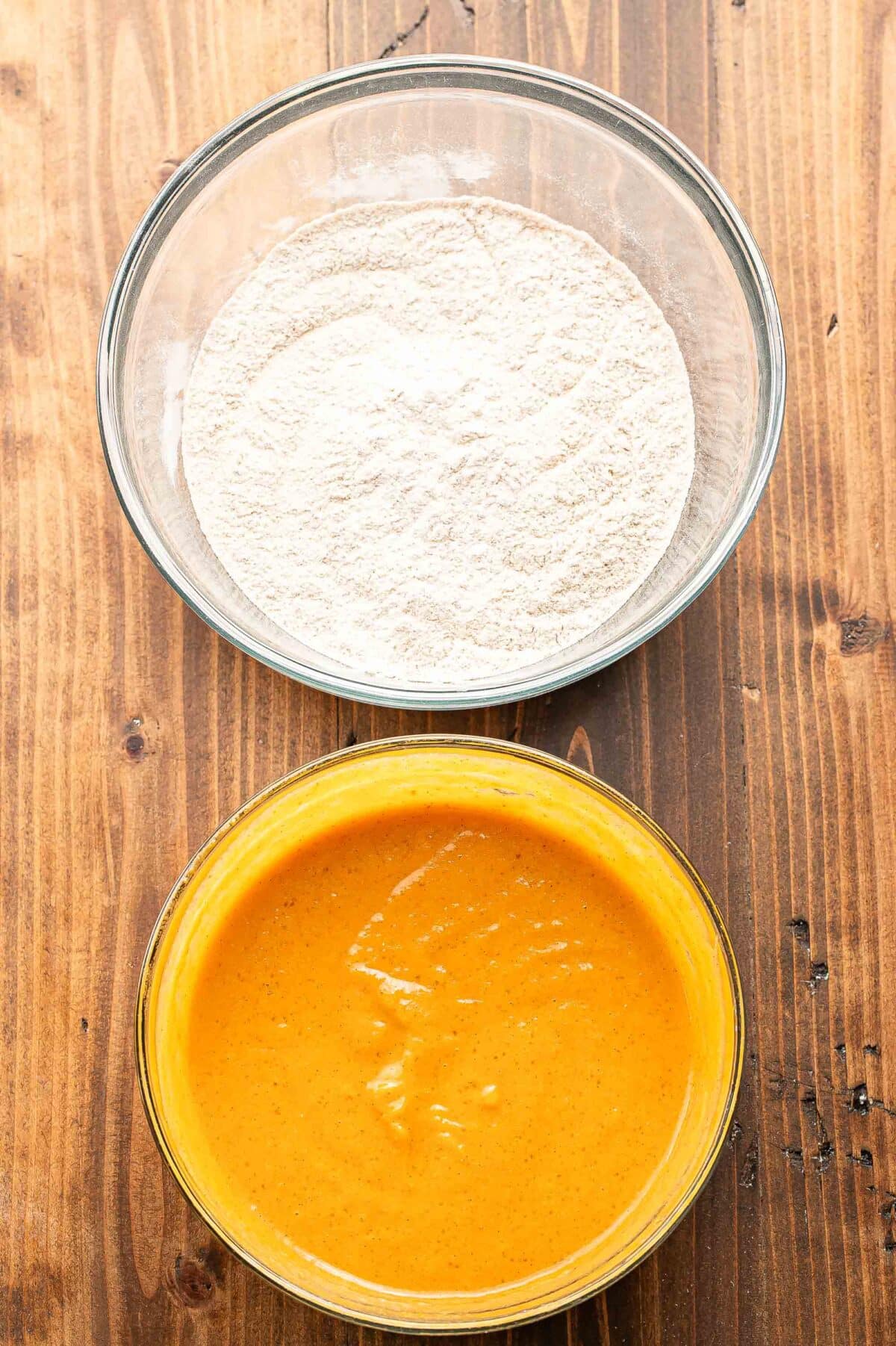 A mixing bowl with the dry ingredients for pumpkin muffins in it and another bowl with the wet ingredients in it.
