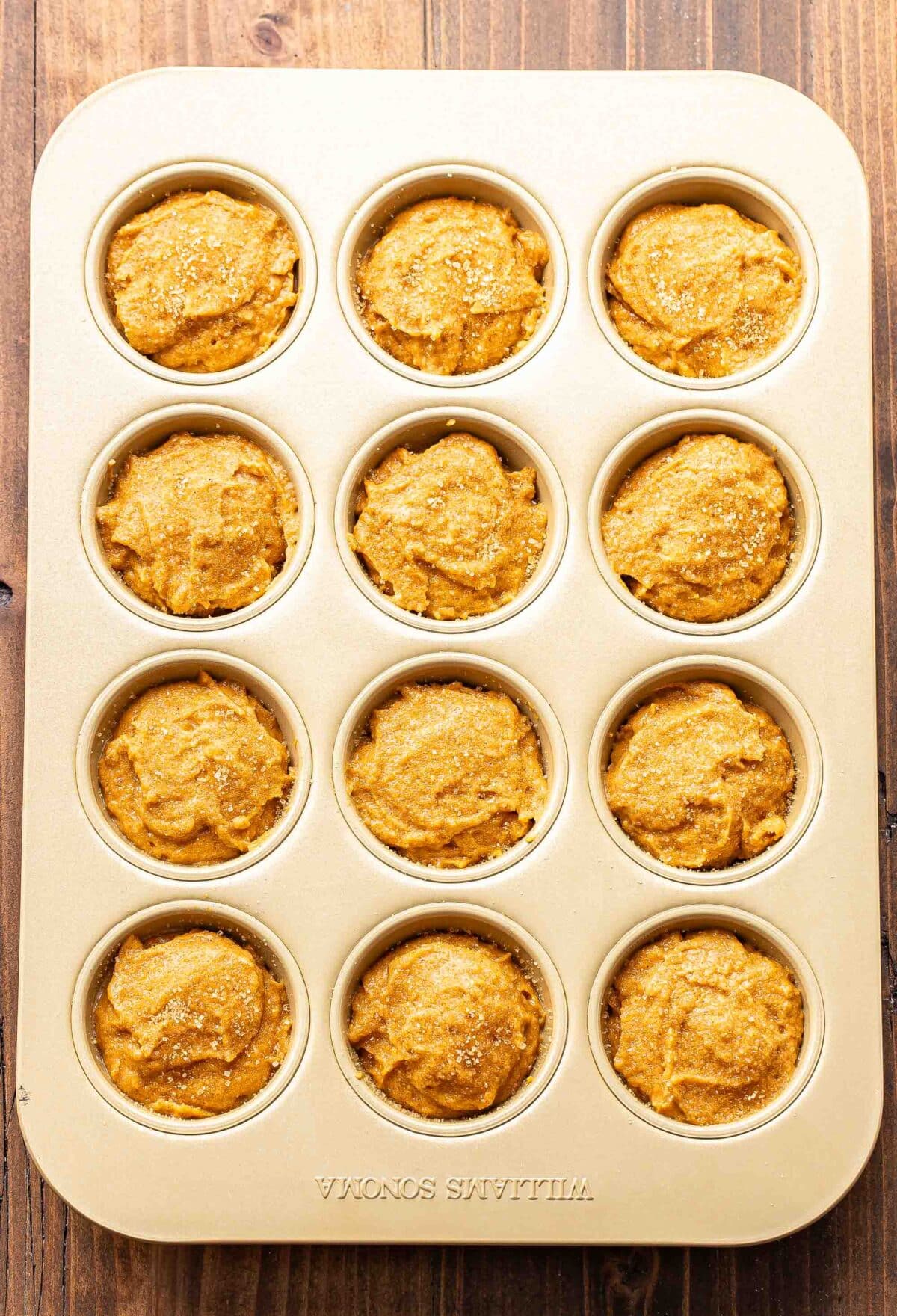 The batter for pumpkin muffins in a muffin pan.