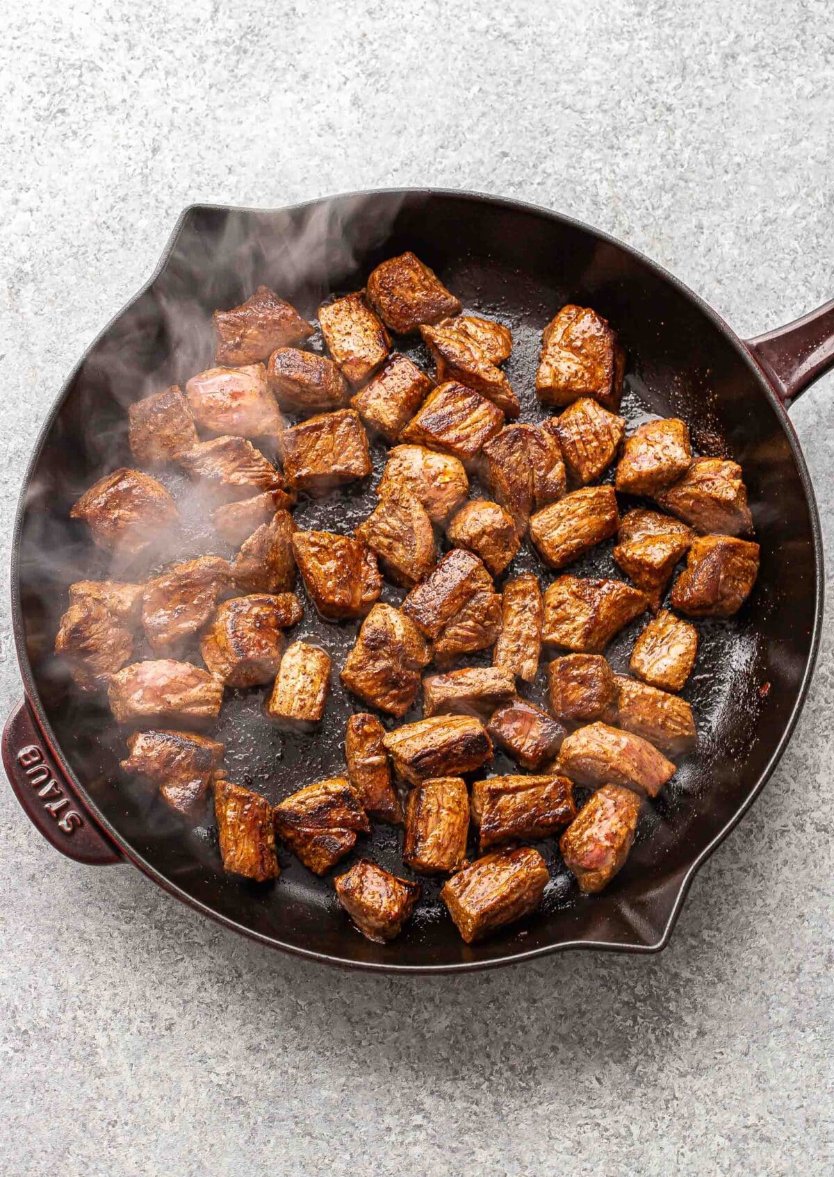 Chunks of cooked steak in a skillet.