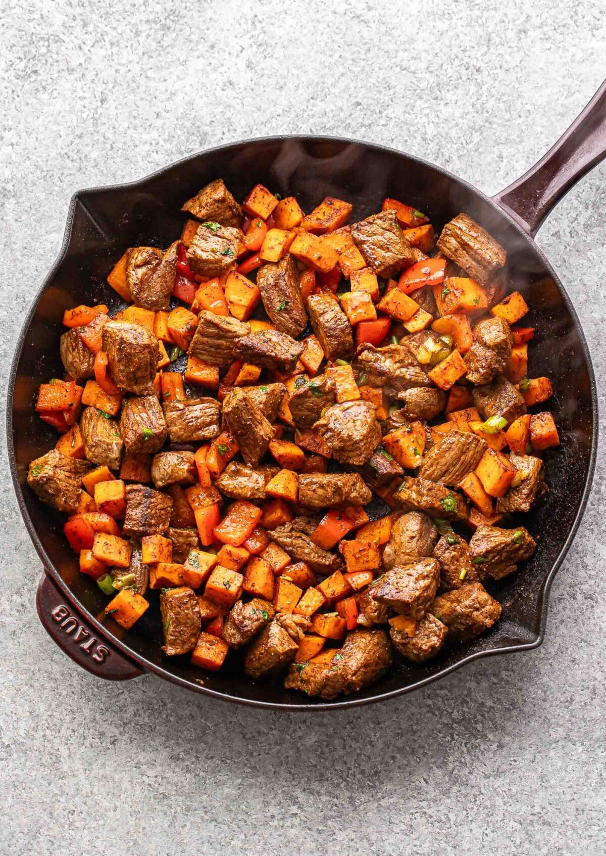 Cooked steak and sweet potatoes in a skillet.