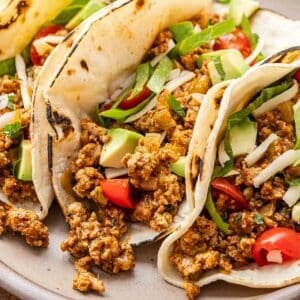 Ground turkey taco topped with lettuce, avocado chunks, and diced tomatoes.