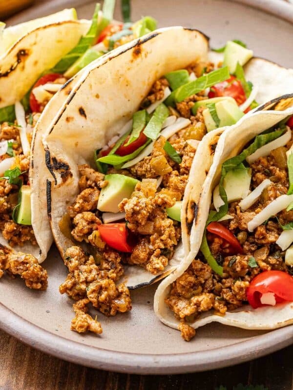 Ground turkey taco topped with lettuce, avocado chunks, and diced tomatoes.