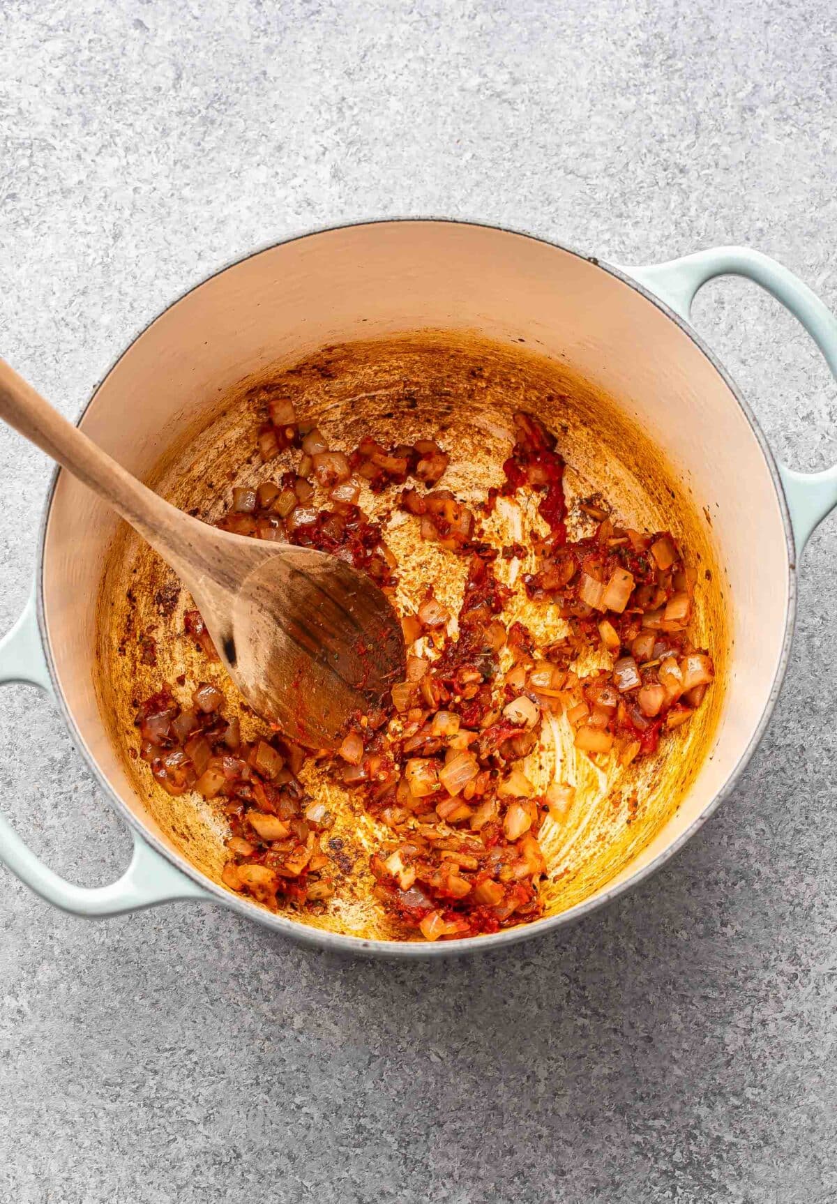 Onions, garlic, and tomato paste in a pot.