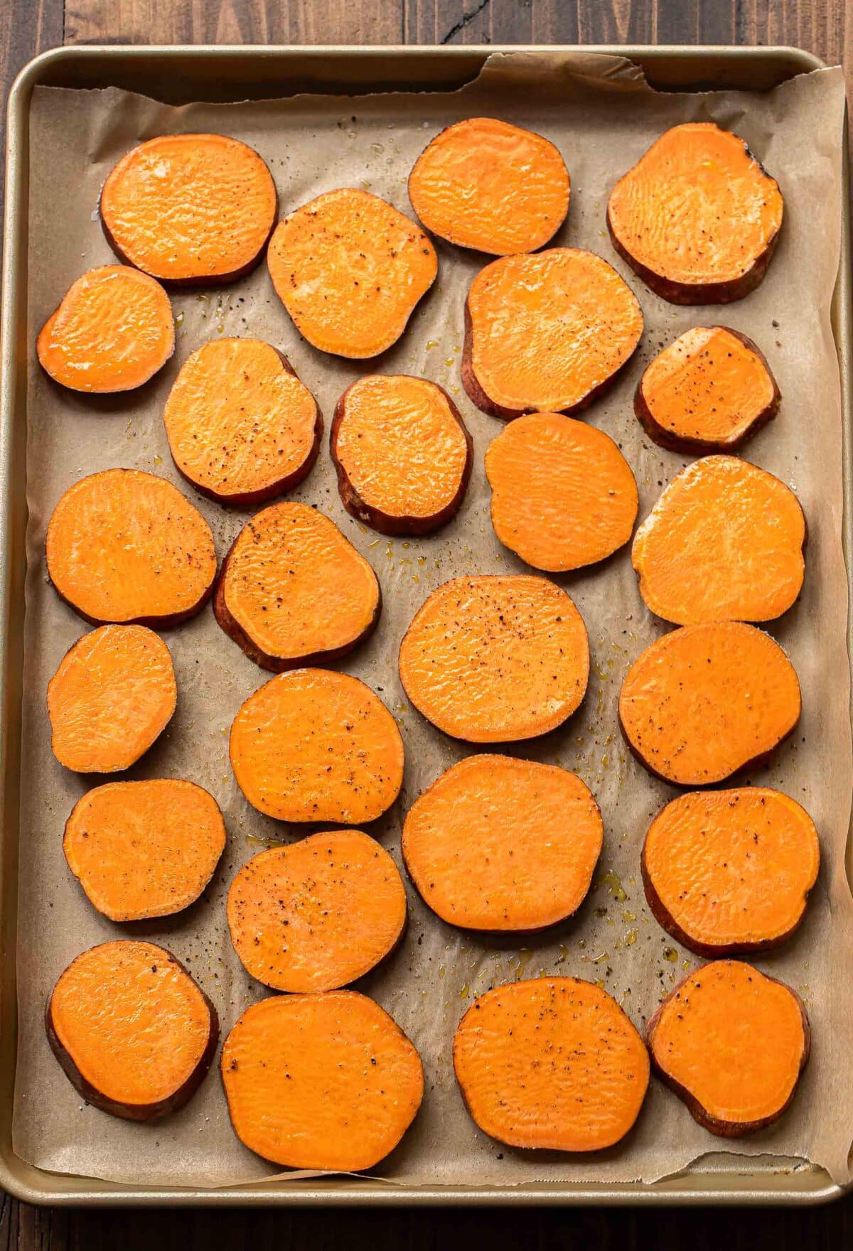 Sweet potato rounds on a parchment paper lined sheet pan.