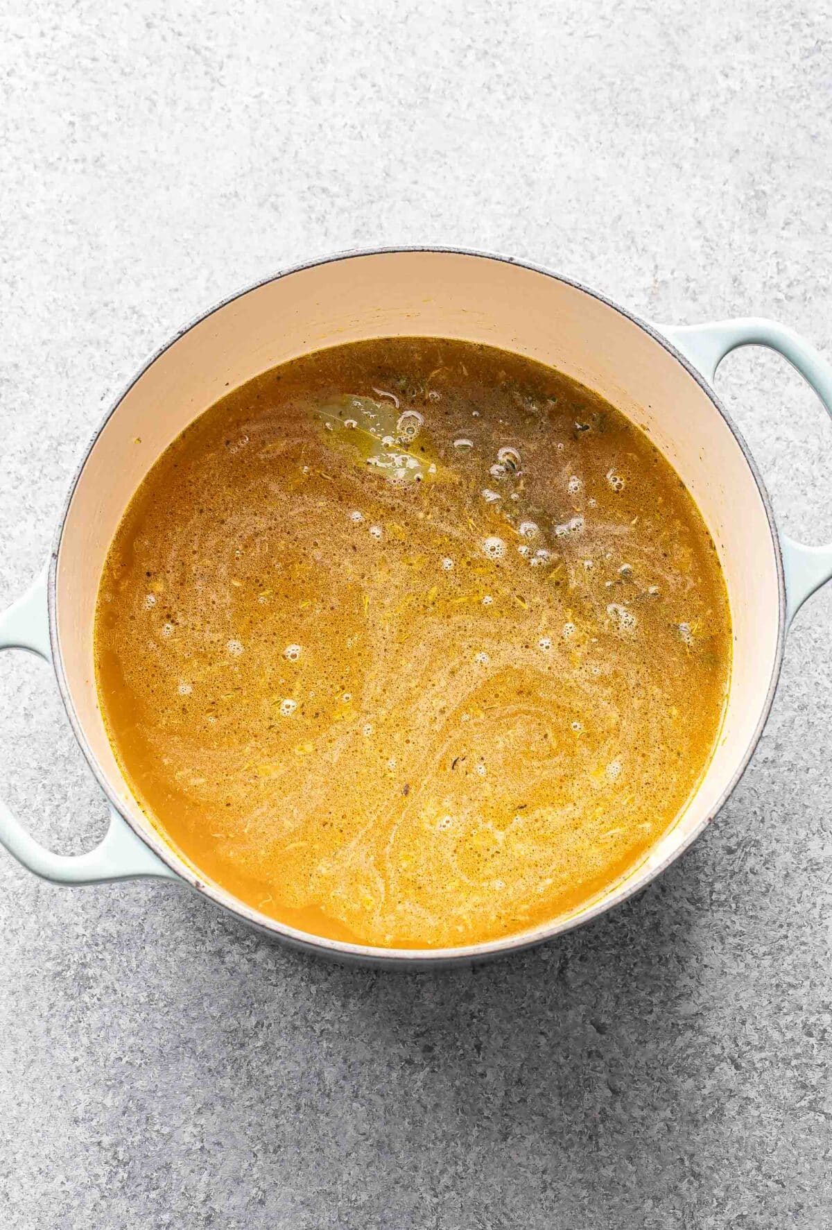 Carrots, celery, onion, thyme, and chicken broth in a pot.