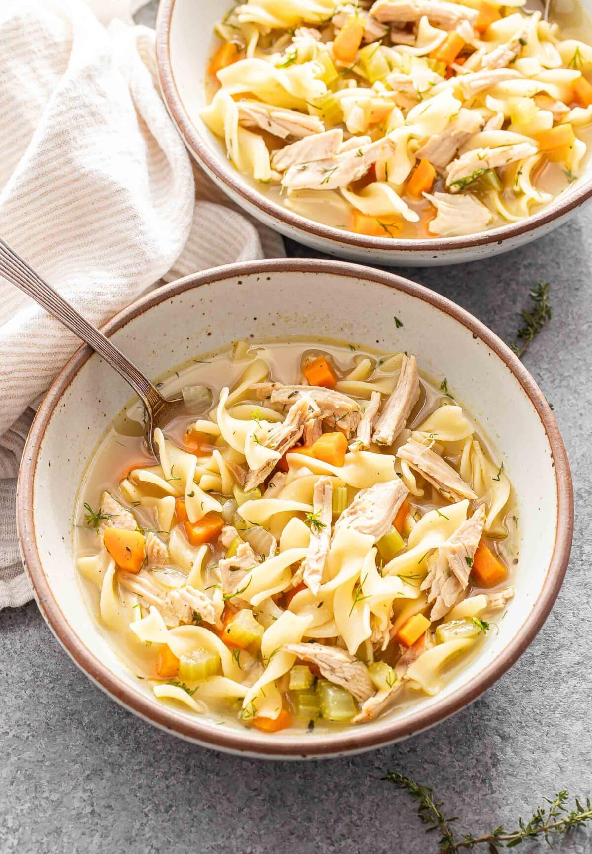 Two white bowls filled with turkey noodle soup.
