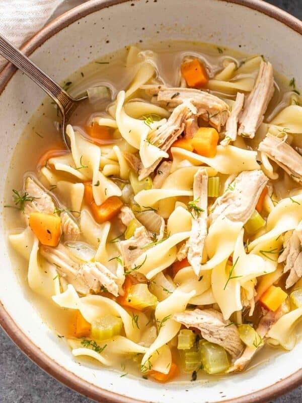 A white bowl with turkey noodle soup in it.