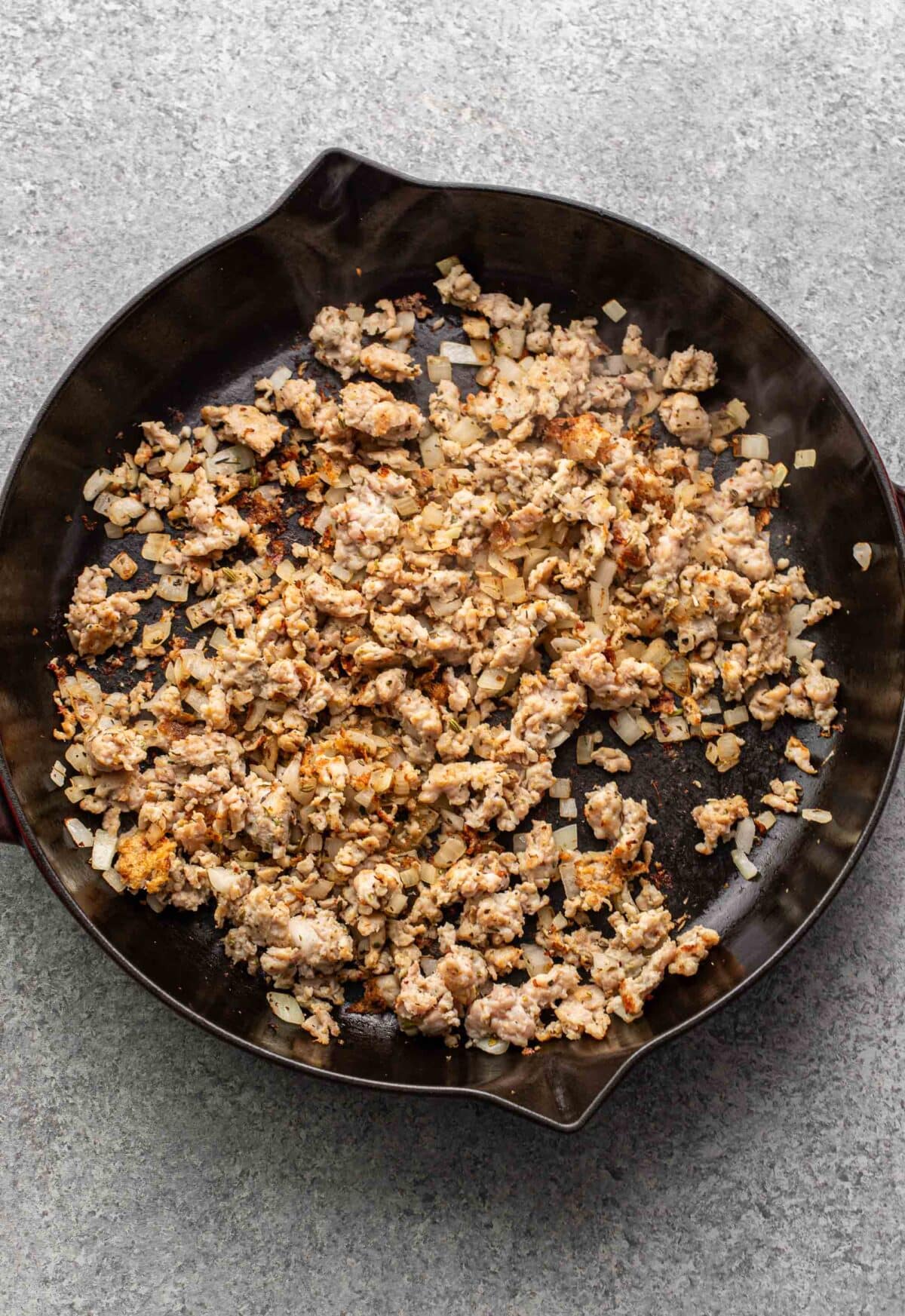 Crumbled Italian sausage and onion in a skillet.