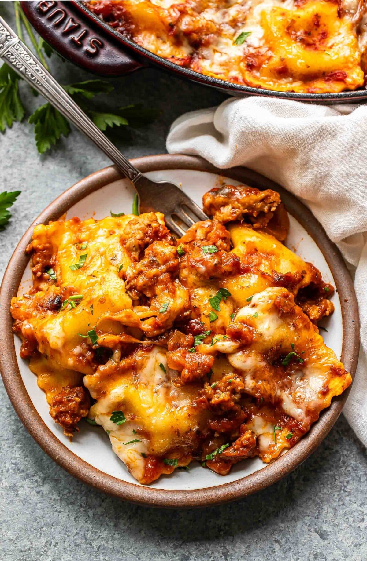 Baked ravioli on a white plate with a fork.