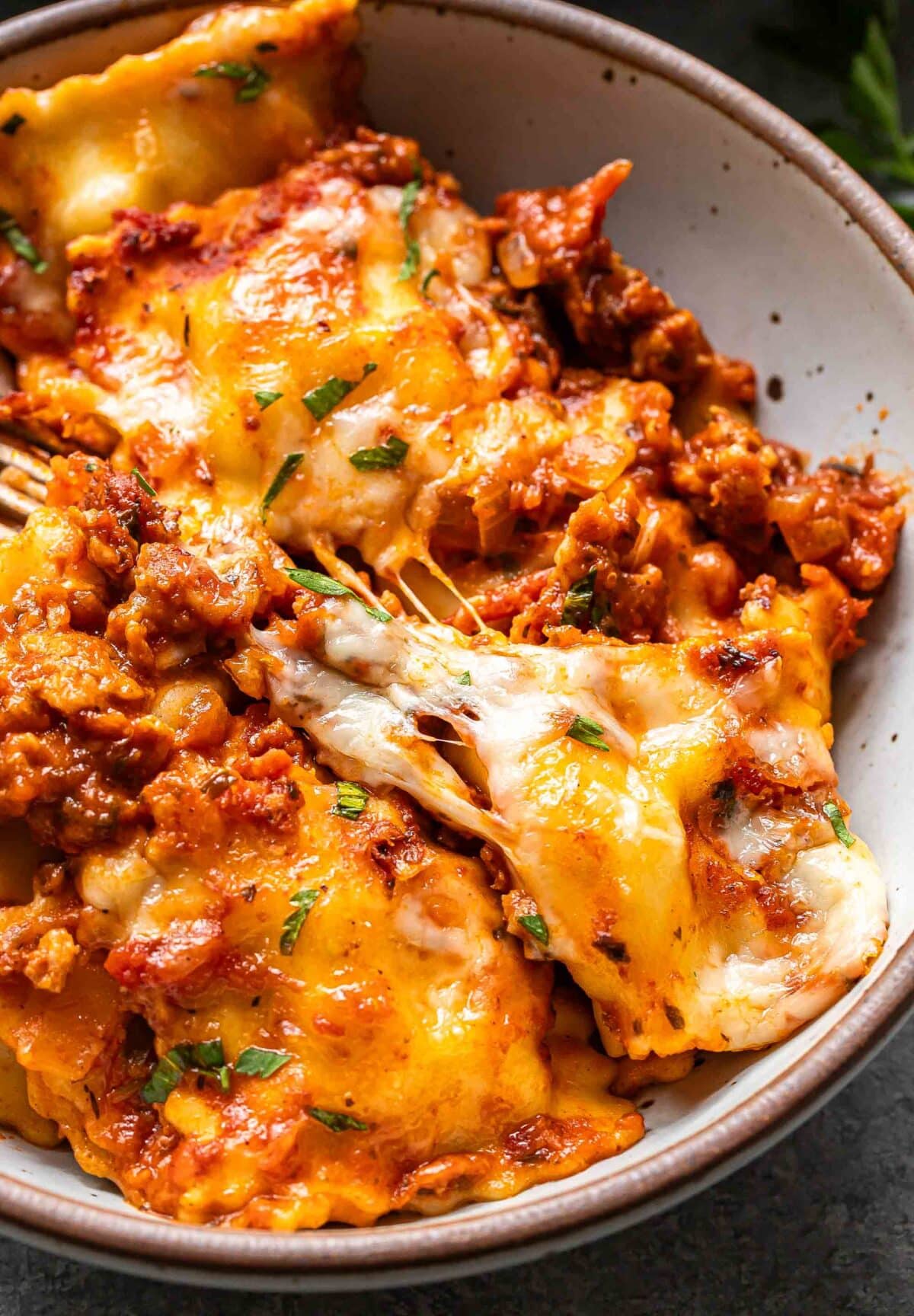 Baked ravioli topped with melted cheese in a white bowl.