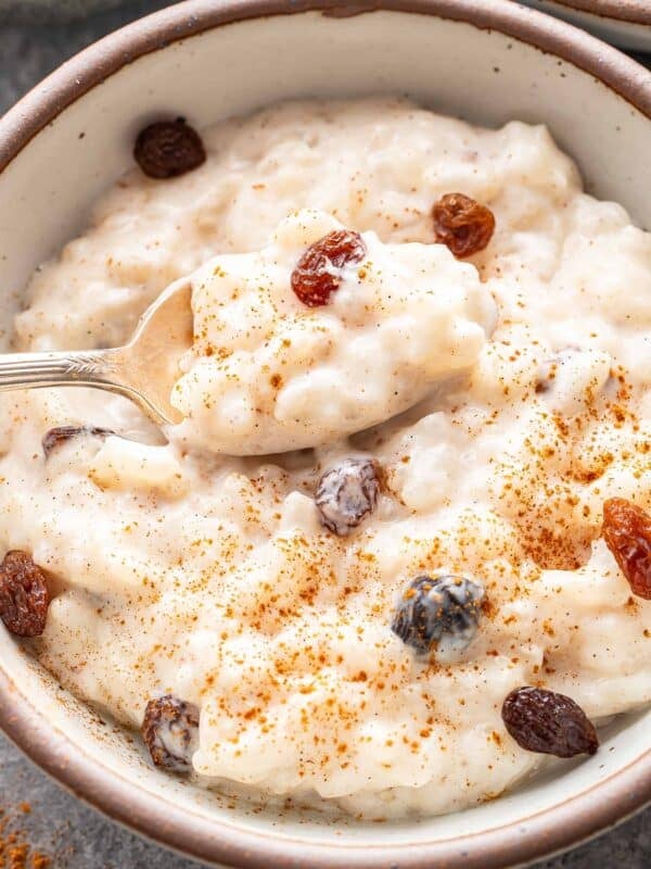Rice pudding in a bowl with a spoon scooping up some of it.