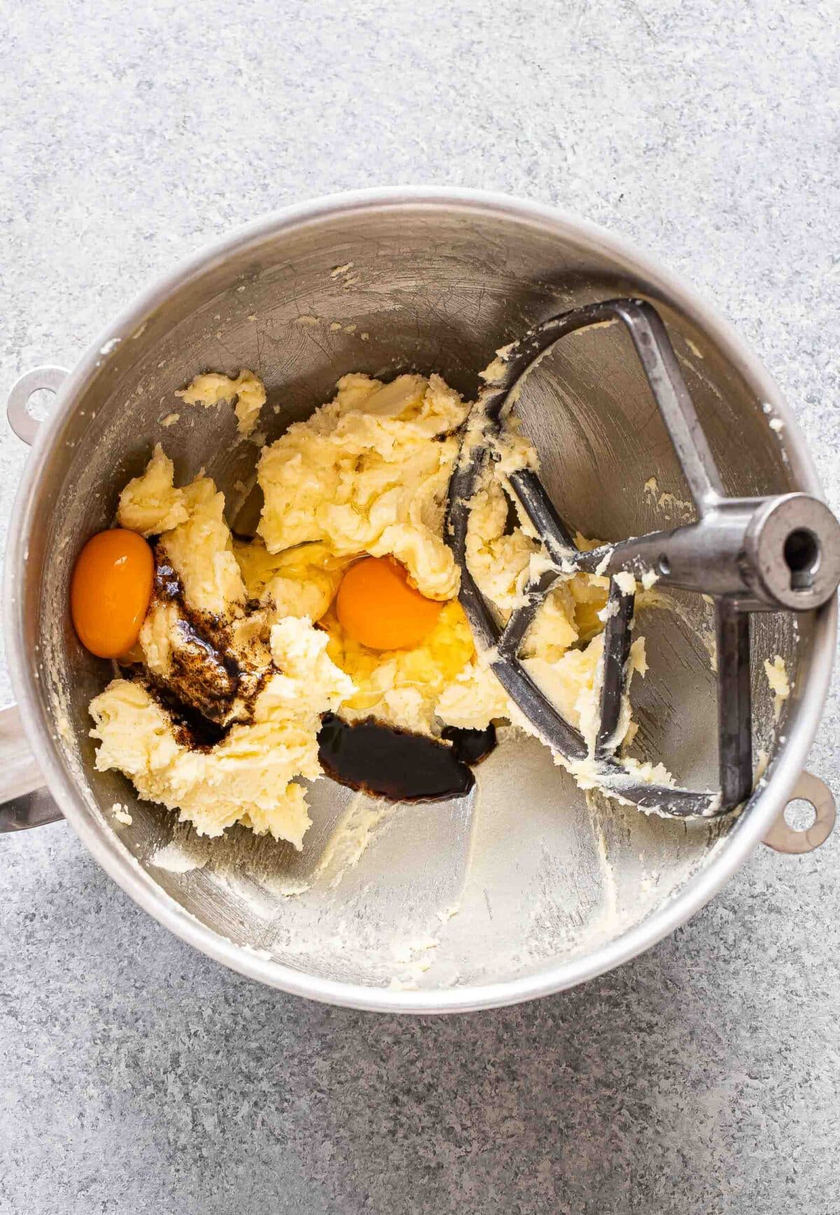 Eggs, vanilla, butter, and sugar in a mixing bowl.