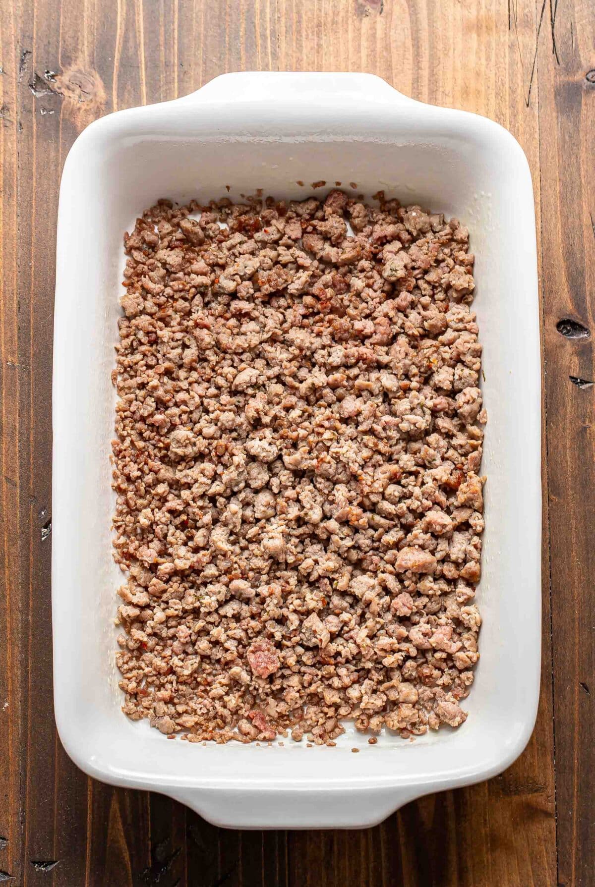 Crumbled breakfast sausage in a white casserole dish.