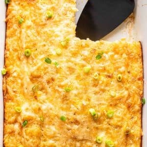 Egg breakfast casserole in a white casserole dish with a piece cut out and a black serving spatula in it's place.