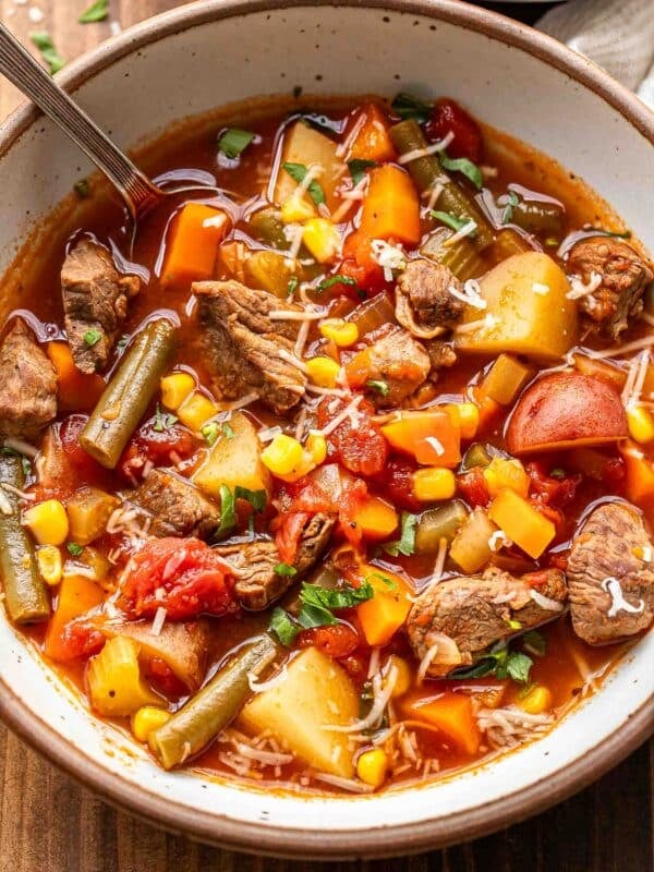 Beef, potato, and vegetable soup in a white bowl with a spoon.