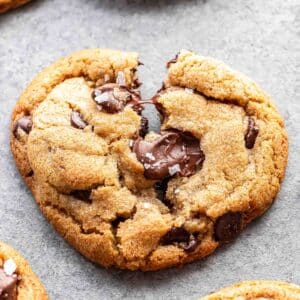 Thick and chewy chocolate chip cookie partially broken in half.