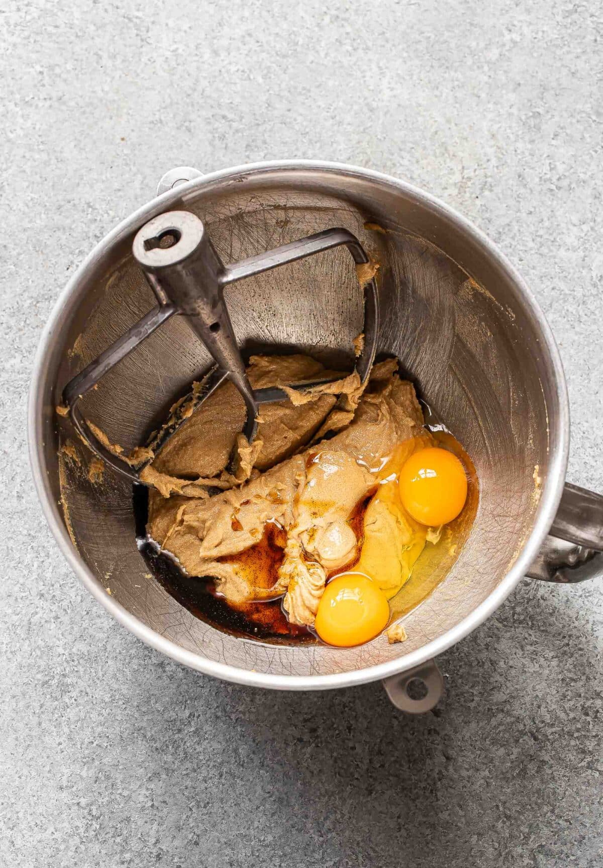 Beaten butter and sugar mixture with two eggs and vanilla in a mixing bowl.