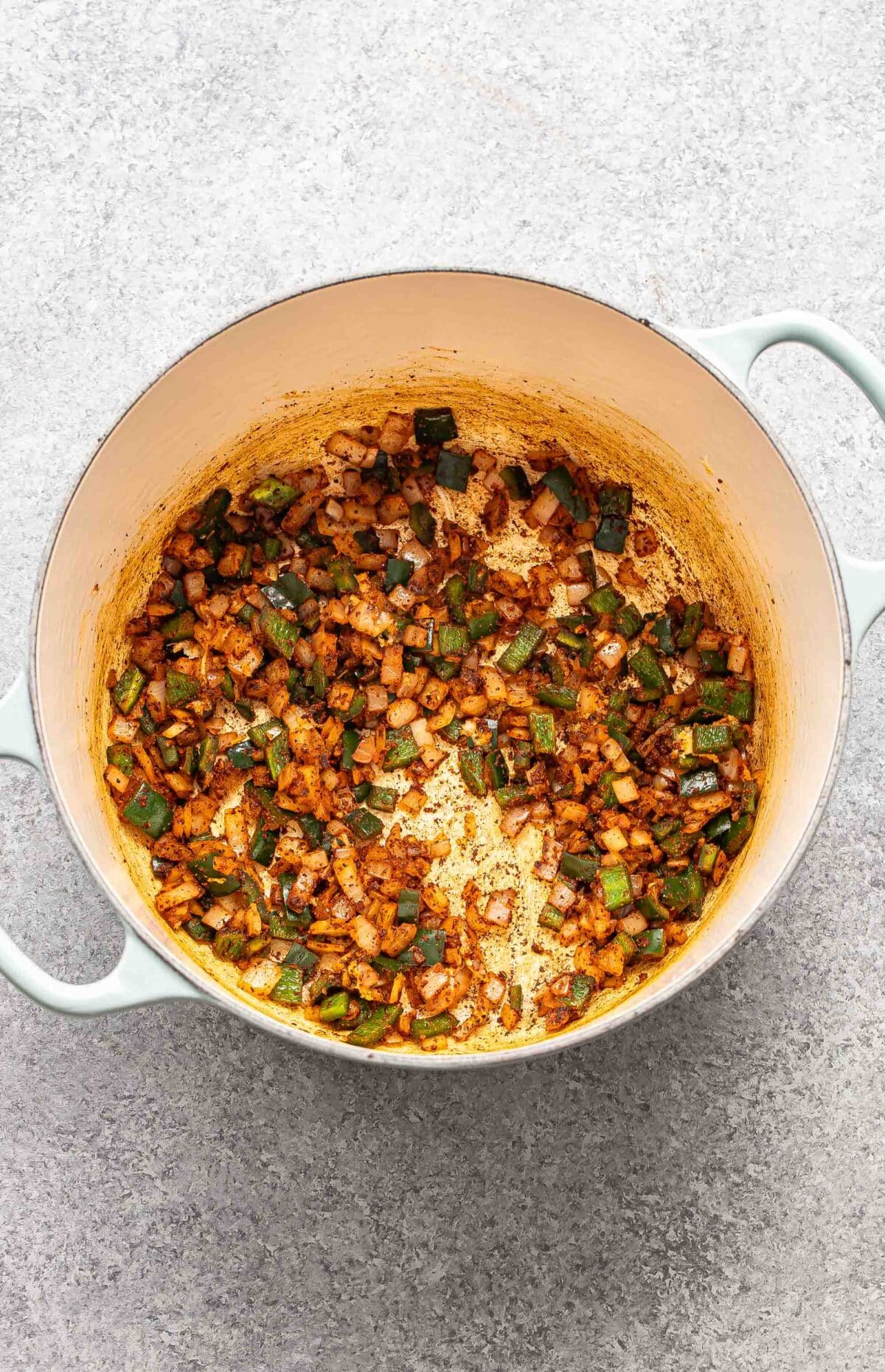 Cooked onions, poblano pepper, and spices in a pot.