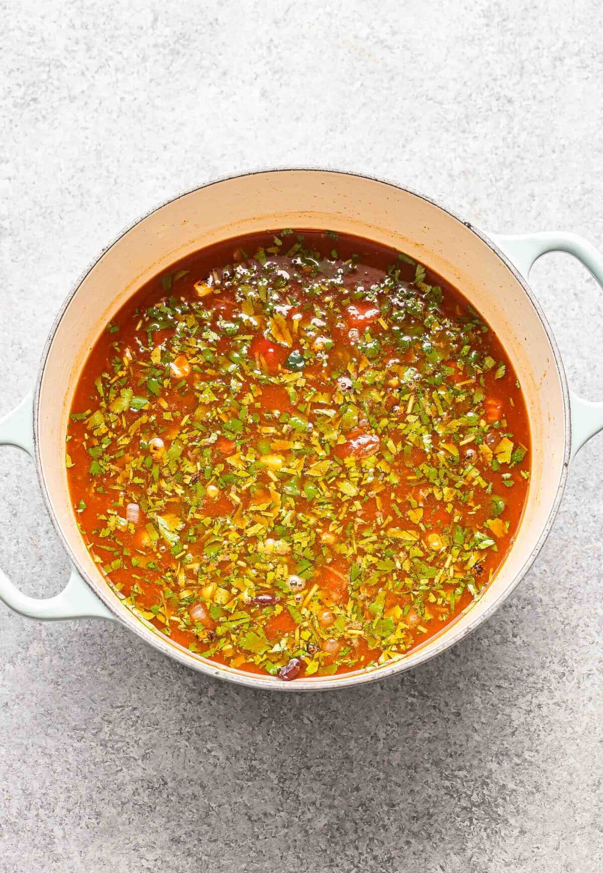 Cooked vegetables, cilantro, and broth in a pot.
