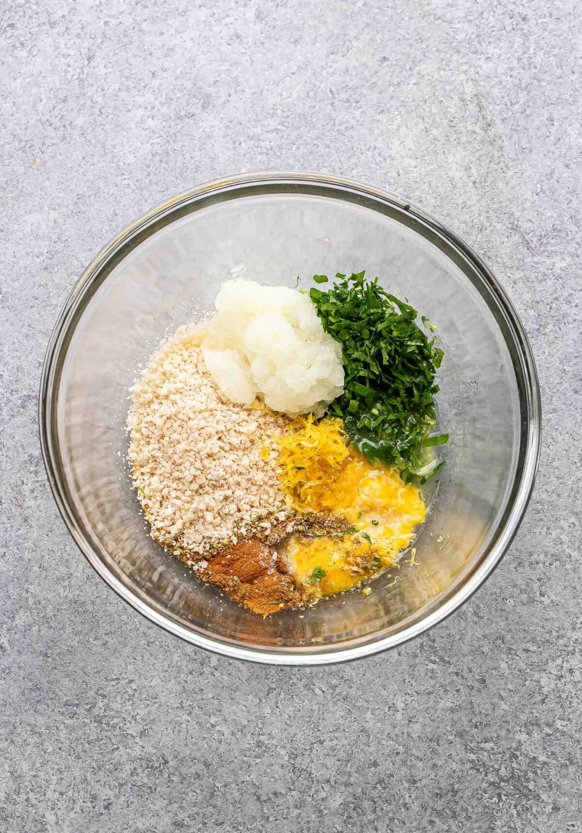 chicken meatball ingredients in glass bowl before being combined together.